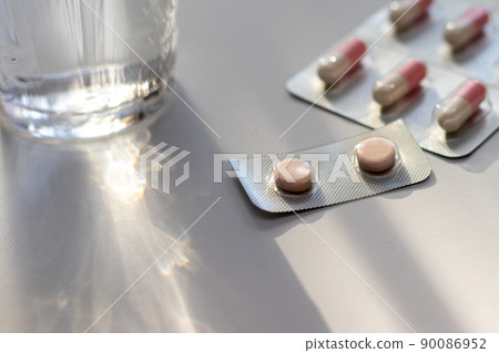 Medicine on a white table and a glass of water 90086952