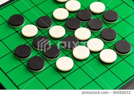Black and white stones of Othello on a green board 90088032