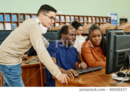 Group of three migrant students searching data in internet on desktop computer in university library Group of three migrant students searching data in internet on desktop computer in university library 90088837