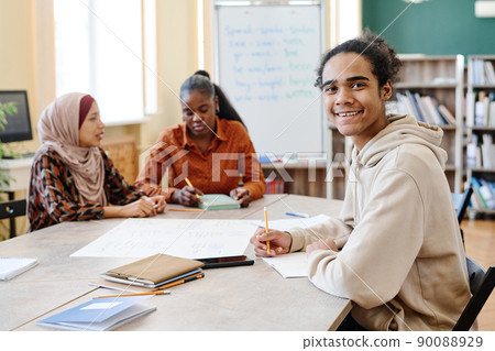Young Black man sitting at table enjoying learning English language at school for immigrants smiling at camera 90088929