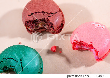 Colorful cake macaron bitten on beige background, pastel color. 90088956