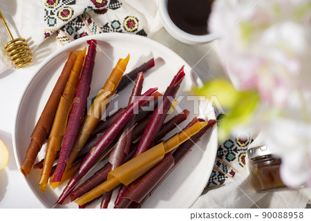 Colorful fruit leather rolls on a plate on light background 90088958