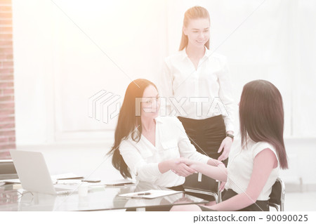 Two business women shake hands with each other above the signed contract Two business women shake hands with each other above the signed contract 90090025