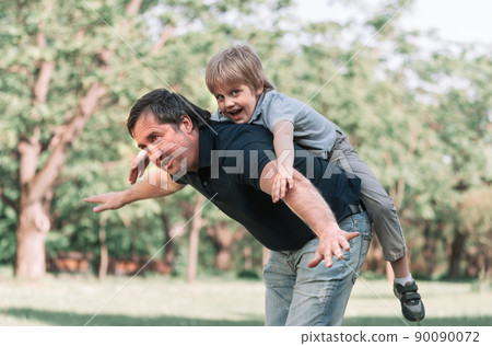 dad plays with his little son on a walk in the Park . dad plays with his little son on a walk in the Park . 90090072
