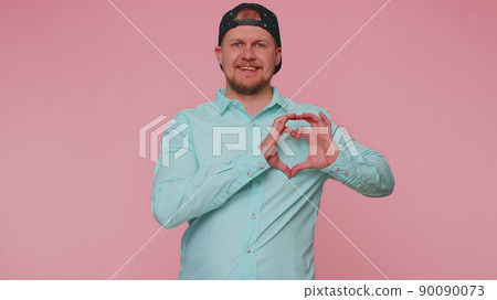 Smiling man makes heart gesture demonstrates love sign expresses good feelings and sympathy Smiling man makes heart gesture demonstrates love sign expresses good feelings and sympathy 90090073