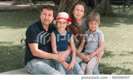 family with children sitting on a city bench 90090097