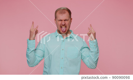 Overjoyed happy man showing rock n roll gesture by hands, cool sign, shouting yeah with crazy face 90090098
