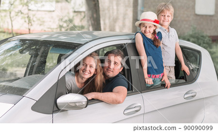 family with two children sitting in their family car. 90090099