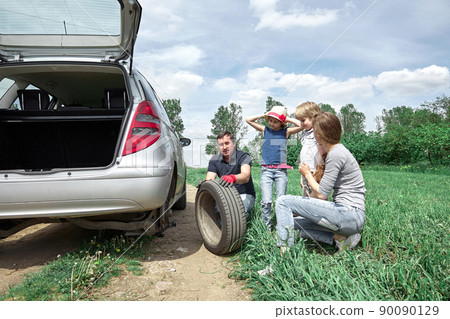 father replaces the damaged tire of the family car. 90090129
