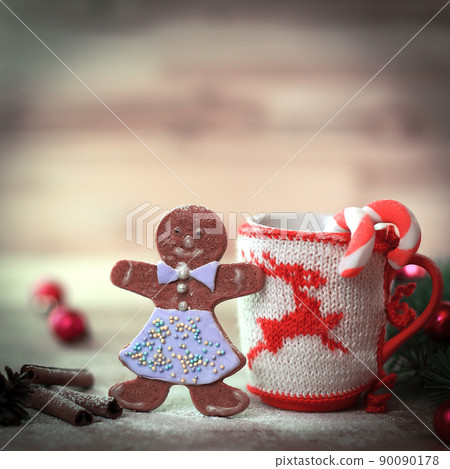 Christmas Cup ornament and a fun gingerbread on a wooden table Christmas Cup ornament and a fun gingerbread on a wooden table 90090178
