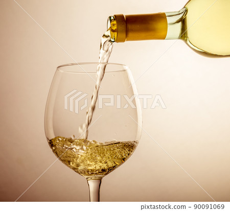 White wine pouring in glass from a bottle 90091069