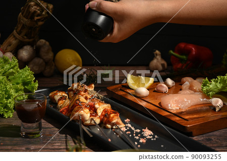 Chef is sprinkling ground pepper on grilled chicken. Barbecue, food, party concept 90093255