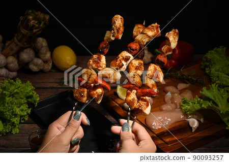 Woman hands holding delicious grilled chicken skewers with tomato, sweet pepper and onions 90093257
