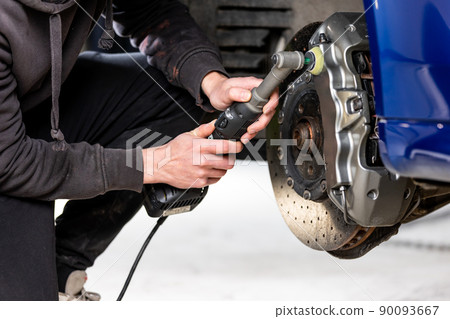 Car detailing - Hand with orbital polisher in auto repair shop, polishing modern car brakes Car detailing - Hand with orbital polisher in auto repair shop, polishing modern car brakes 90093667