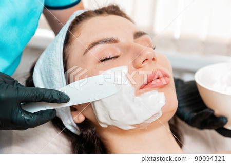 Cosmetologist in latex gloves applying with spatula rejuvenation mask on the client's face. Close up. Concept of professional cosmetology and beauty treatment Cosmetologist in latex gloves applying with spatula rejuvenation mask on the client's face. Close up. Concept of professional cosmetology and beauty treatment 90094321