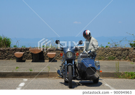 A driver checking a sidecar and taking a break at the beach parking A driver checking a sidecar and taking a break at the beach parking 90094963