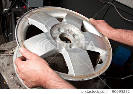 Mechanic changing car wheel in auto repair shop 90095222