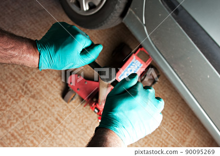 Close up of car lifted with car jack at auto mechanic workshop. Close up of car lifted with car jack at auto mechanic workshop. 90095269