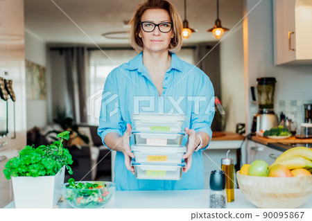 Healthy diet plan for weight loss, daily ready meal menu. Woman holding lunch boxes just cooked in advance, ready to be served. Containers with eco healthy food. Pre-cooking concept. Selective focus. Healthy diet plan for weight loss, daily ready meal menu. Woman holding lunch boxes just cooked in advance, ready to be served. Containers with eco healthy food. Pre-cooking concept. Selective focus. 90095867