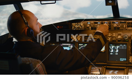 Airline captain fixing altitude and longitude to fly airplane, using dashboard command and control panel to takeoff. Flying plane jet with radar compass and handle for navigation. Handheld shot. Airline captain fixing altitude and longitude to fly airplane, using dashboard command and control panel to takeoff. Flying plane jet with radar compass and handle for navigation. Handheld shot. 90096258