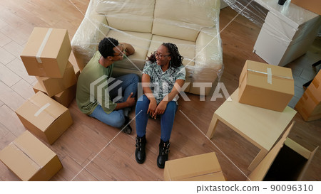 African american couple dreaming about family in new house, taking break on floor after moving in. Homeowners feeling happy about relocation and future lifestyle. Handheld shot. Top view. African american couple dreaming about family in new house, taking break on floor after moving in. Homeowners feeling happy about relocation and future lifestyle. Handheld shot. Top view. 90096310