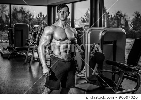Handsome man with big muscles, posing at the camera in the gym Handsome man with big muscles, posing at the camera in the gym 90097020
