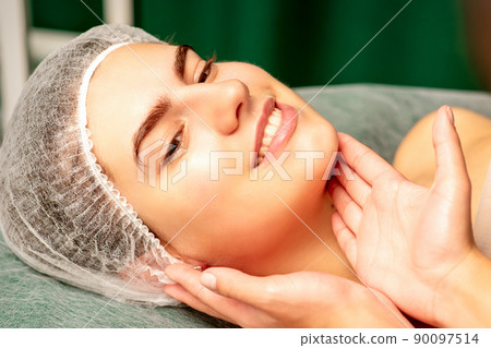 Plastic surgery and beauty concept. Professional cosmetician examining and touching the face of the beautiful young caucasian smiling woman in a clinic of esthetic cosmetology Plastic surgery and beauty concept. Professional cosmetician examining and touching the face of the beautiful young caucasian smiling woman in a clinic of esthetic cosmetology 90097514