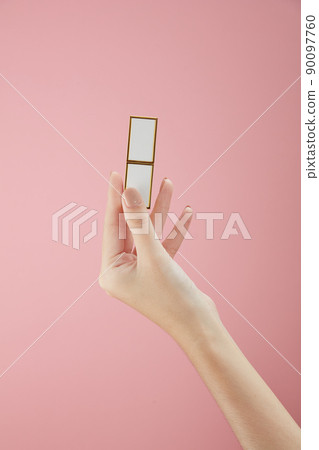 Top view of hand model holding lipstick on hand in pink background for cosmetic advertising Top view of hand model holding lipstick on hand in pink background for cosmetic advertising 90097760