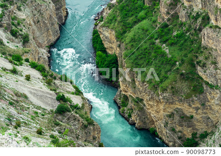 top view of a fast mountain river flowing at the bottom of a deep canyon 90098773