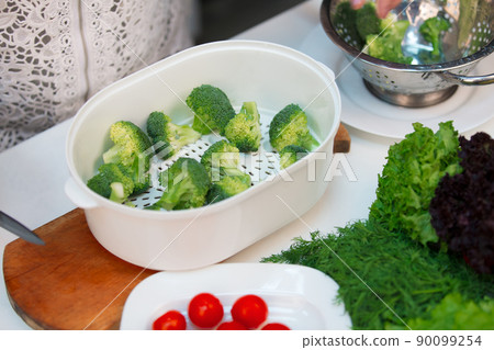 Cooking broccoli in a double boiler in the kitchen Cooking broccoli in a double boiler in the kitchen 90099254
