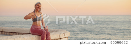 Asian lady in sportswear sitting on the edge of seafront 90099622