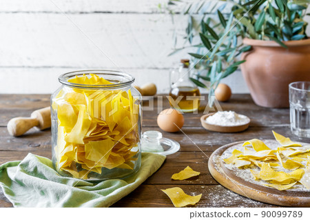 Homemade pasta Maltagliat in jar and wooden cutting boardi with ingredients in rustic style 90099789