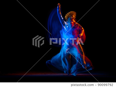 Stylish man dancing hip-hop in sportive style clothes isolated on dark background at dance hall in mixed neon light. Youth culture, hip-hop, movement Stylish man dancing hip-hop in sportive style clothes isolated on dark background at dance hall in mixed neon light. Youth culture, hip-hop, movement 90099792