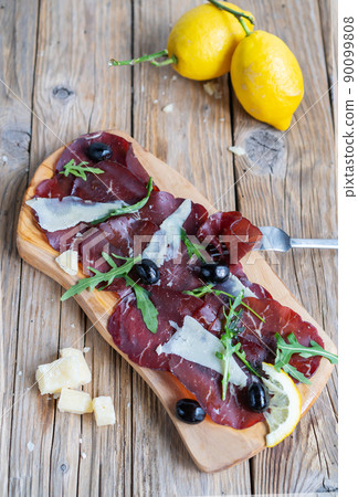 Jerky meat bresaola with lemons, grana and arugula Jerky meat bresaola with lemons, grana and arugula 90099808
