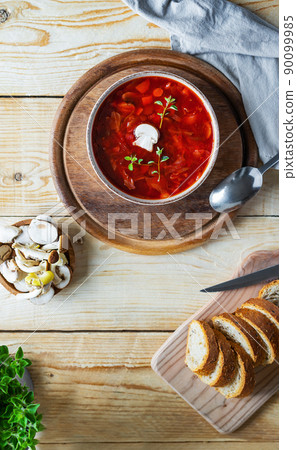 Vegan beetroot soup with mushrooms in a bowl, bread, raw mushrooms and oregano on a wooden background Vegan beetroot soup with mushrooms in a bowl, bread, raw mushrooms and oregano on a wooden background 90099985