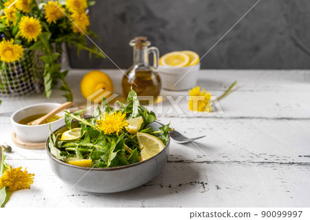Dandelion salad with olive oil, lemon juice and spices on white wooden table with grey background. Copy space Dandelion salad with olive oil, lemon juice and spices on white wooden table with grey background. Copy space 90099997