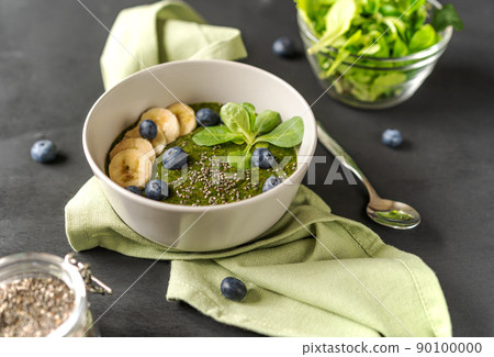 Green porridge in bowl with main ingredients: chia seeds, greens on the black background with napkin Green porridge in bowl with main ingredients: chia seeds, greens on the black background with napkin 90100000