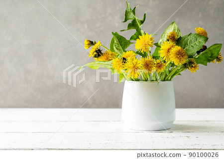 Mock up creation. White wooden table with grey concrete background, dandelions in vase and copy space on the left Mock up creation. White wooden table with grey concrete background, dandelions in vase and copy space on the left 90100026