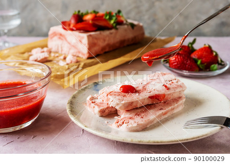 Italian strawberry dessert Semifreddo on plate with teaspoon pouring strawberry's sauce 90100029