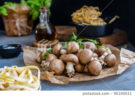 Raw mushrooms champignons with fresh pasta, olive oil, spices and basil plant on grey background Raw mushrooms champignons with fresh pasta, olive oil, spices and basil plant on grey background 90100031