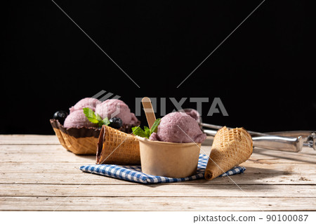 Blueberry ice cream scoops with waffle on wooden table 90100087