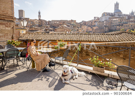 Young woman having lunch, sitting with a dog at outdoor restaurant in Siena town Young woman having lunch, sitting with a dog at outdoor restaurant in Siena town 90100684
