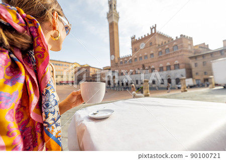 Woman having breakfast at outdoor cafe with beautiful view on main square of Siena city, Italy Woman having breakfast at outdoor cafe with beautiful view on main square of Siena city, Italy 90100721