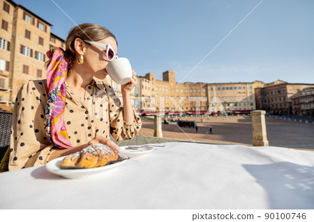 Woman having breakfast at outdoor cafe with beautiful view on main square of Siena city, Italy Woman having breakfast at outdoor cafe with beautiful view on main square of Siena city, Italy 90100746
