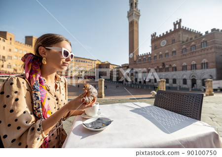 Woman having breakfast at outdoor cafe with beautiful view on main square of Siena city, Italy Woman having breakfast at outdoor cafe with beautiful view on main square of Siena city, Italy 90100750