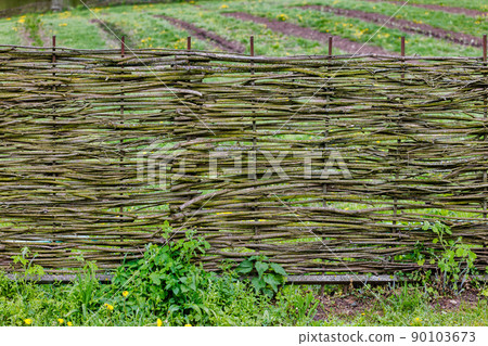 horizontal wattle fence in front of rustic garden 90103673