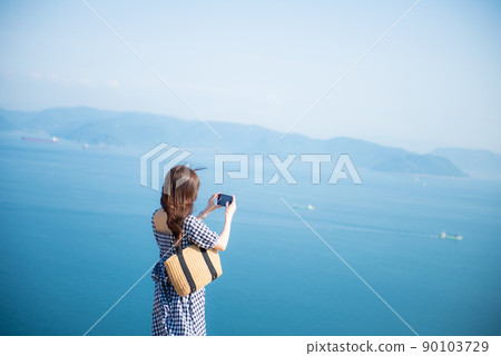 A woman pointing her camera at the blue sea A woman pointing her camera at the blue sea 90103729