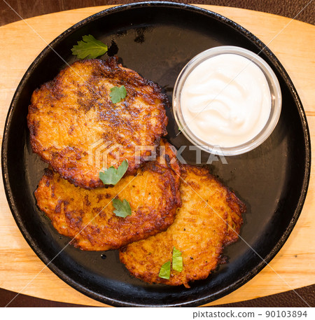 Fried grated potato pancakes with sour cream on frying pan. top of view 90103894