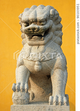 Zhenjiang, Jiangsu Province, China: A traditional Chinese lion statue against a yellow background at Dinghui Temple in Zhenjiang. 90103951