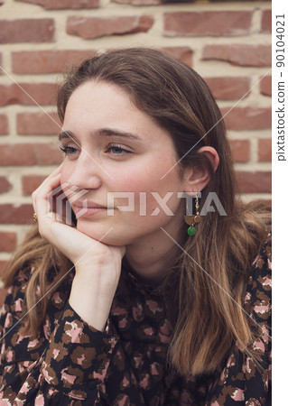 Close up portrait of joyless 20s woman sitting alone near indoor wall. Face of caucasian serious 90104021